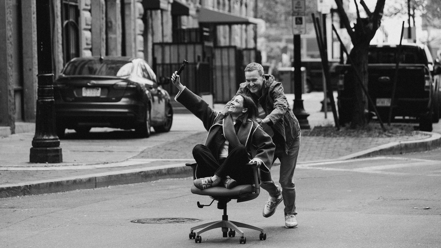 a man pushes a woman in an office chair down a street in Boston