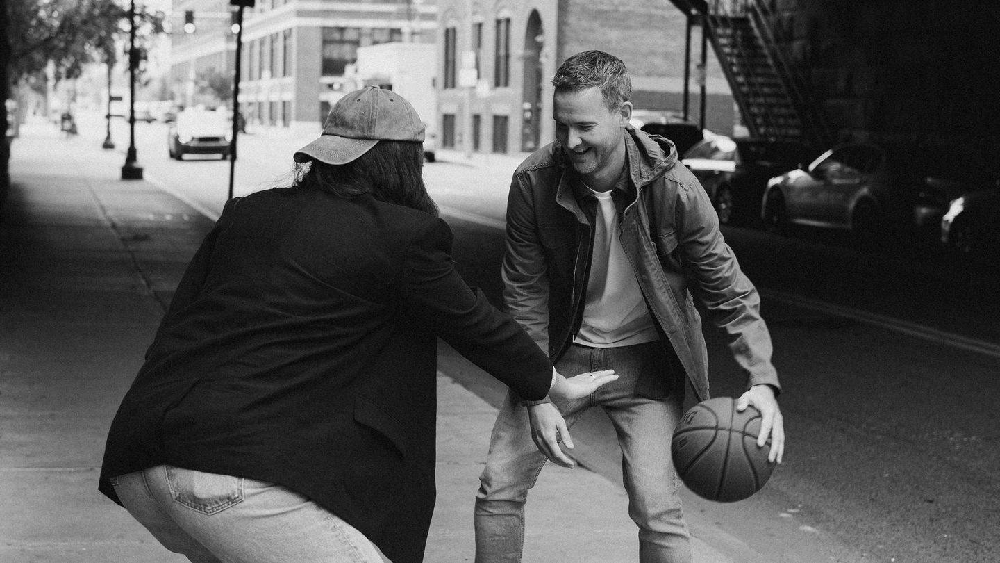Two people play basketball on the sidewalk in Boston's seaport